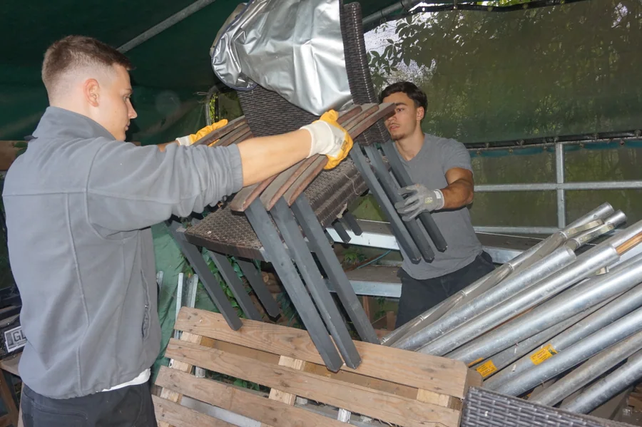 Martin und Nuri tragen gemeinsam Gartenstühle